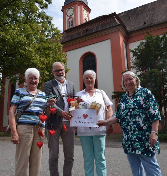Quelle: Hubert Bleyer, Ein Herz für St. Margarethen und für die Kirchenrenovierung: Pfarrer Thomas Braunstein nimmt von Klärle Hamma (von links), Elisabeth Rantz und von Anneliese Birth, der Leiterin des Strickkreises, eine Spende des Strickkreises des Seniorenwerks vom Verkaufserlös des Standes beim St. Margarethenfest entgegen.